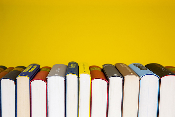 Colorful row of upright books against a vibrant yellow background